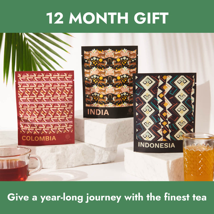 An assortment of tea bags from Colombia, India and Indonesia are next to each other, surrounded by green tropical leaves and cups of tea on a white background.