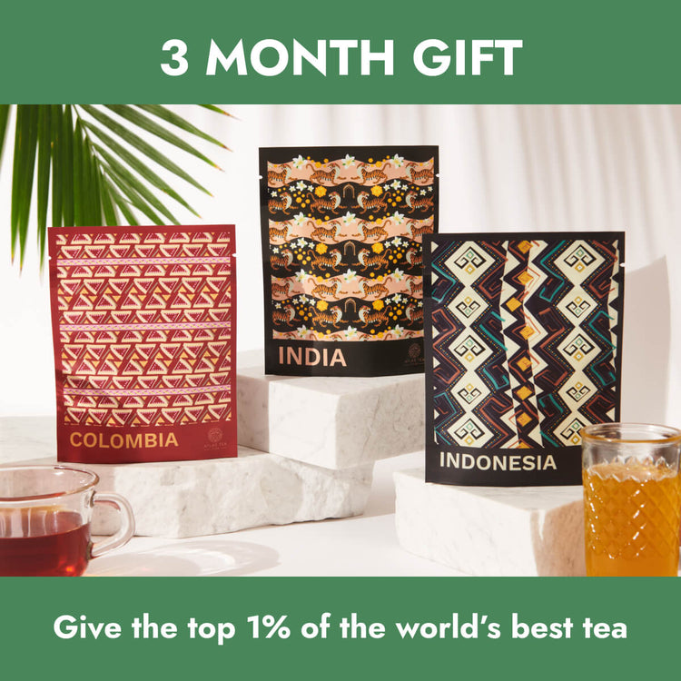 An assortment of tea bags from Colombia, India and Indonesia are next to each other, surrounded by green tropical leaves and cups of tea on a white background.