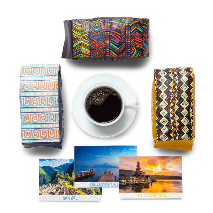 An assortment of coffee bags and postcards around a cup of coffee.